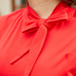 Close-up of bow neckline detail on red sleeveless top