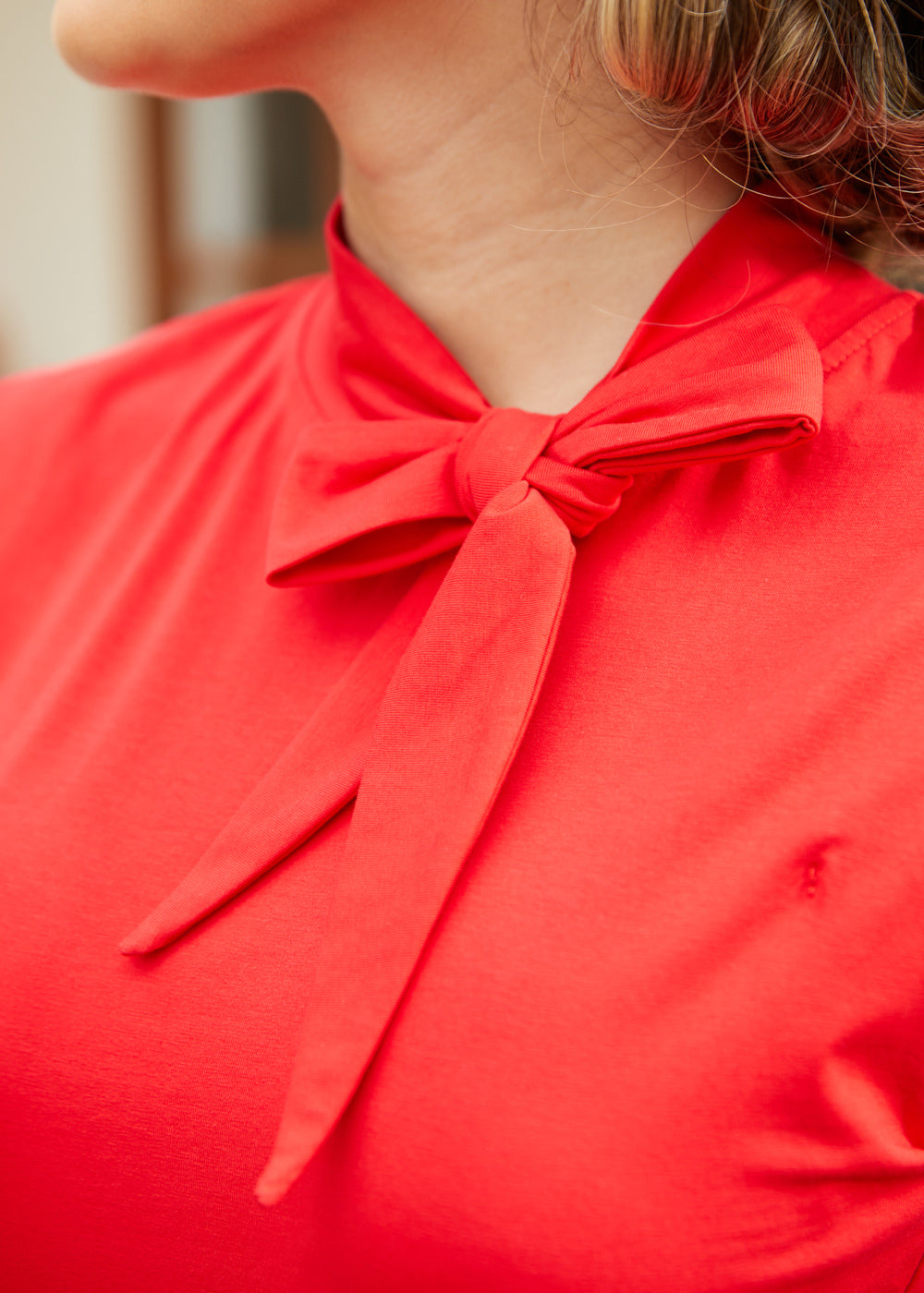 Close-up of bow neckline detail on red sleeveless top