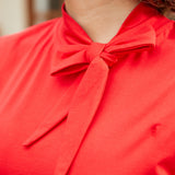Close-up of bow neckline detail on red sleeveless top