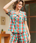 Woman wearing a colorful plaid outfit in an outdoor setting