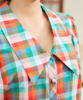 Close-up of oversized collar and button-front detail in retro check pattern