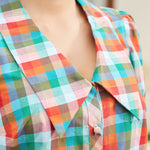 Close-up of oversized collar and button-front detail in retro check pattern