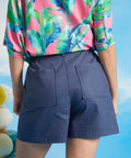 Back view of blue linen blend shorts with elastic waistband and patch pockets.