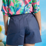 Back view of blue linen blend shorts with elastic waistband and patch pockets.