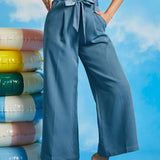 Woman wearing dusty blue high-waisted cropped wide leg pants with sash tie belt and pockets paired with a striped sleeveless top