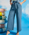 Person wearing blue wide-leg pants with a colorful striped top against a blue sky background.