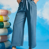 Person wearing blue wide-leg pants with a colorful striped top against a blue sky background.