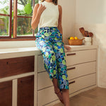 Woman in a white top and blue patterned pants standing in a kitchen.
