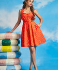 Woman wearing orange retro-inspired sundress with novelty aquatic print and full skirt