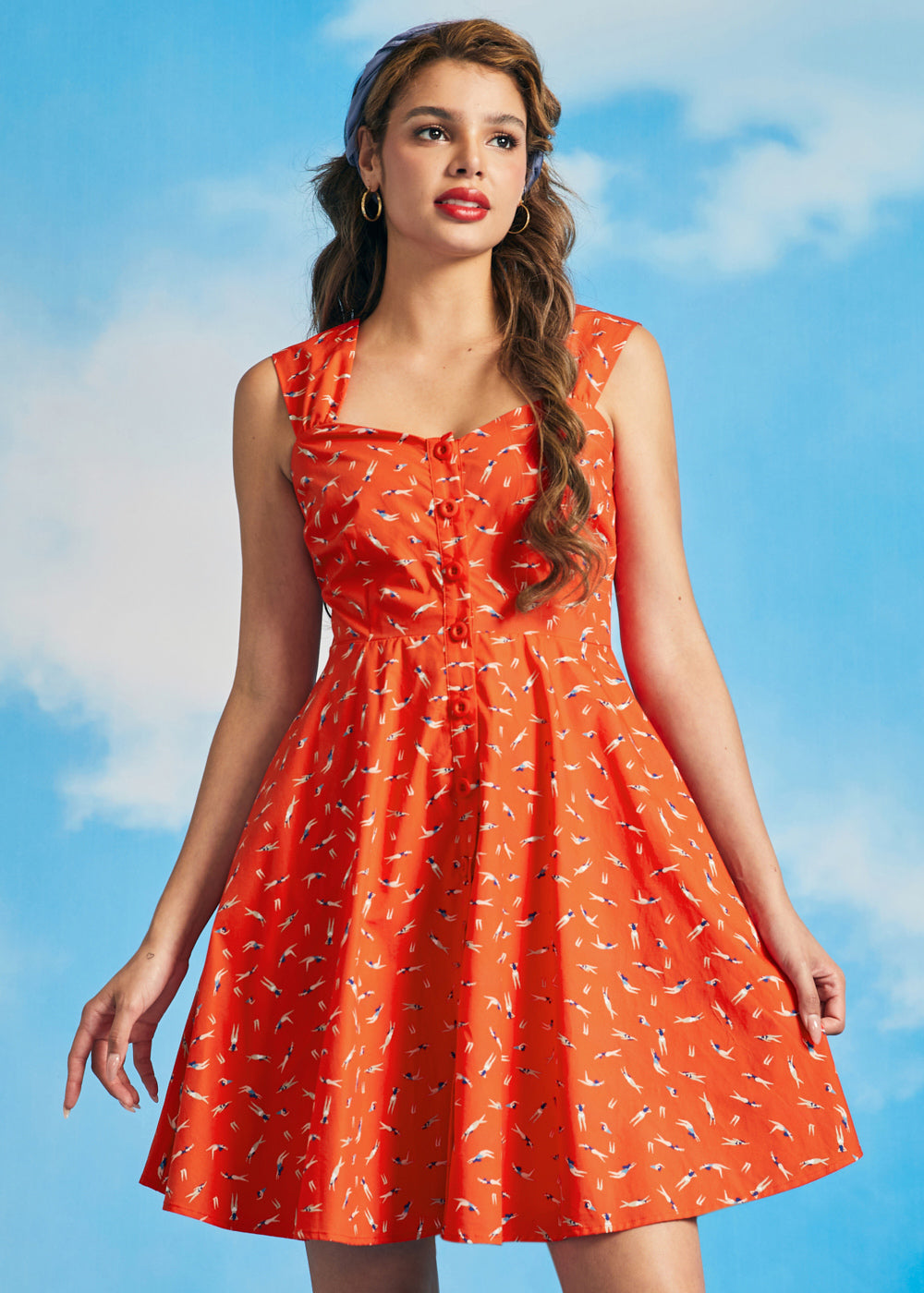 Woman wearing orange vintage-inspired sundress with synchronized swimmer novelty print and sweetheart neckline