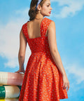 Back view of orange sleeveless sundress with smocked back panel and novelty swim print