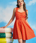 Woman posing in vintage-inspired orange summer dress with swimmer print and pockets