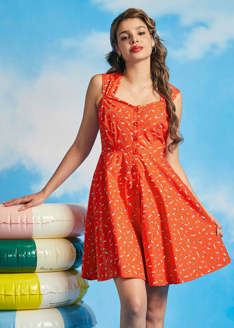 Woman posing in vintage-inspired orange summer dress with swimmer print and pockets