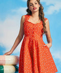 Woman wearing retro orange fit-and-flare sundress with swimmer print and pockets