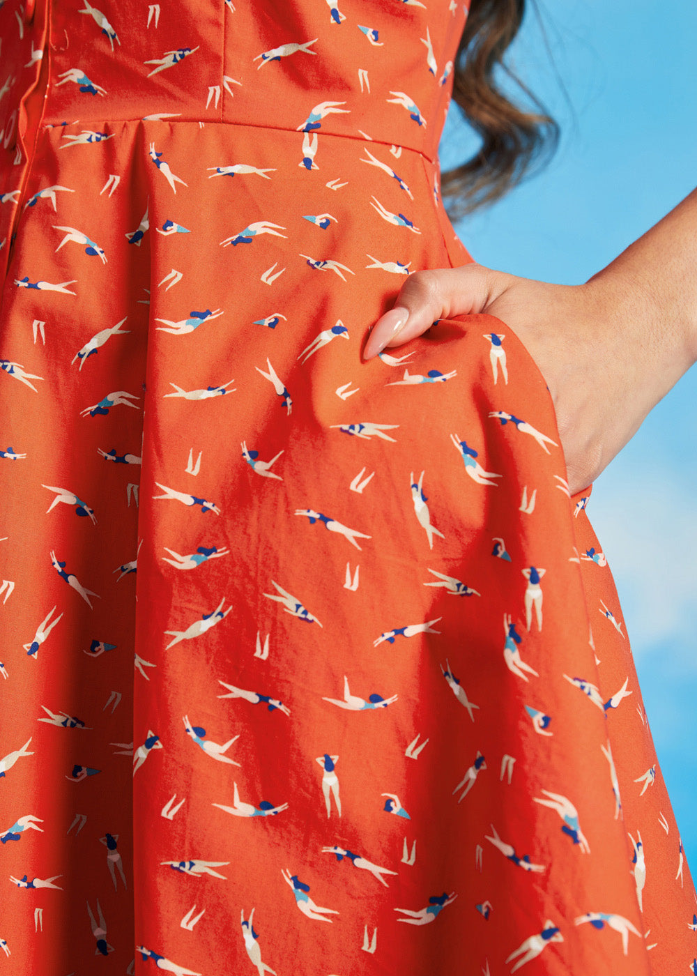 Close-up of orange cotton sundress with synchronized swimmer print and pockets