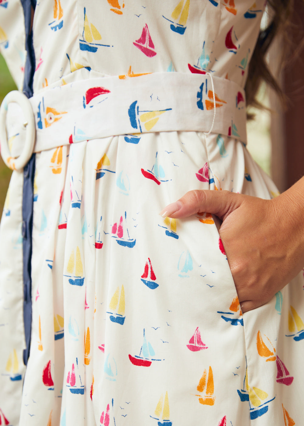 Woman showing side seam pocket on full skirt dress with sail boat print
