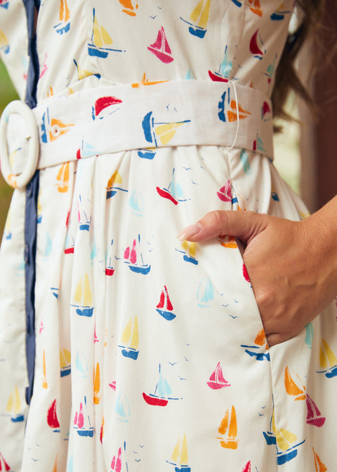 Woman showing side seam pocket on full skirt dress with sail boat print