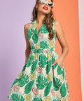 Woman wearing retro tropical print sleeveless dress with pockets and full skirt