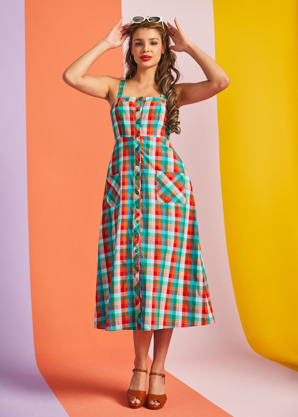Woman wearing colorful rainbow plaid midi dress with button front and pockets