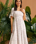 Woman wearing a vintage-inspired smocked midi dress with puff sleeves and side pockets.