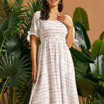 Woman wearing a vintage-inspired smocked midi dress with puff sleeves and side pockets.