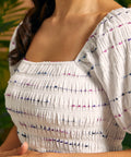Close-up of the smocked square neckline and textured multicolor stripe fabric.
