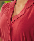 Close-up detail view of a woman wearing a vintage red button bodice dress with a relaxed collar and soft draped fabric.