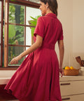 Back view of a woman wearing a short-sleeve, collared, knee-length red vintage inspired dress.