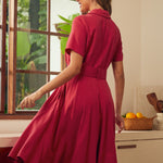 Back view of a woman wearing a short-sleeve, collared, knee-length red vintage inspired dress.