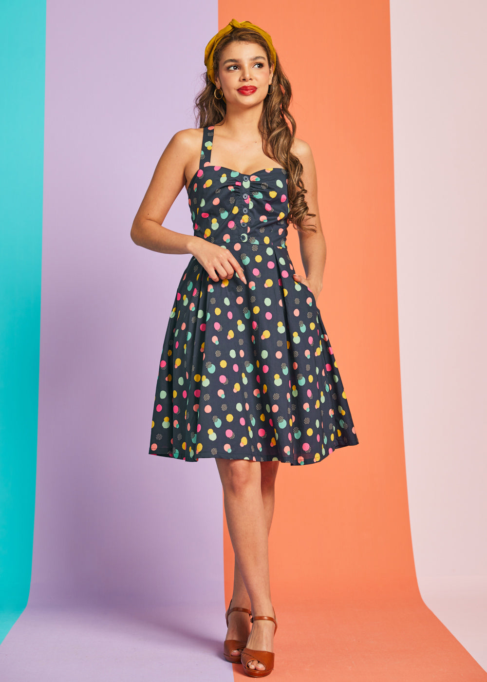 Woman wearing navy retro mini dress with colorful polka dot print and sweetheart neckline