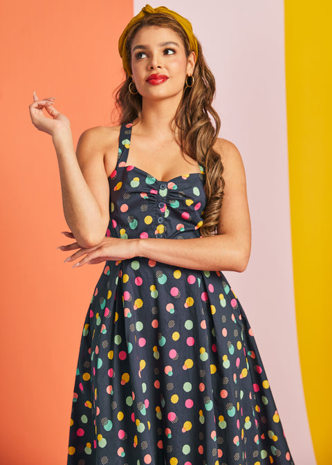 Woman wearing navy polka dot party dress with fit-and-flare silhouette