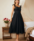 Side angle of black fit and flare dress with flutter straps and layered tulle skirt