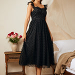 Side angle of black fit and flare dress with flutter straps and layered tulle skirt