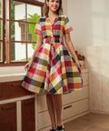 Woman wearing a vintage-inspired wine plaid dress with a full twirl-ready skirt.