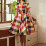 Woman wearing a vintage-inspired wine plaid dress with a full twirl-ready skirt.