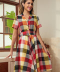 Woman wearing a retro fit-and-flare plaid dress with a notched collar and button-front bodice.