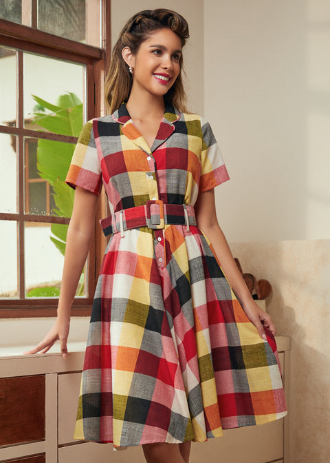 Woman wearing a retro fit-and-flare plaid dress with a notched collar and button-front bodice.