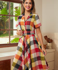 Woman wearing a wine plaid fit-and-flare shirt dress with a removable belt and short sleeves.