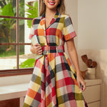 Woman wearing a wine plaid fit-and-flare shirt dress with a removable belt and short sleeves.
