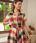Woman wearing a vintage-inspired belted plaid dress in warm harvest-inspired colors.