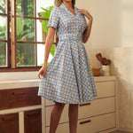 Woman wearing a vintage-inspired cherry print plaid dress with a full skirt.