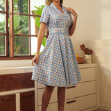 Woman wearing a vintage-inspired cherry print plaid dress with a full skirt.
