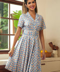 Woman wearing a vintage-inspired blue plaid dress with cherry print and short sleeves.
