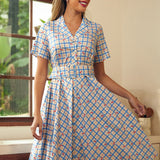 Woman wearing a blue cherry plaid fit-and-flare shirt dress with a removable belt.