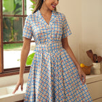 Woman wearing a retro cotton dress featuring tiny cherry motifs and a notched collar.