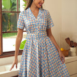 Woman wearing a retro cotton dress featuring tiny cherry motifs and a notched collar.
