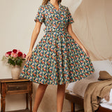 Woman wearing a navy floral fit-and-flare shirt dress with a removable matching belt.