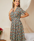 Woman wearing a floral dress in a room with a couch and flowers.
