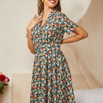 Woman wearing a floral dress in a room with a couch and flowers.