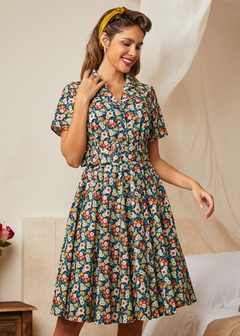 Woman wearing a vintage floral shirt dress with short sleeves and a gathered skirt.